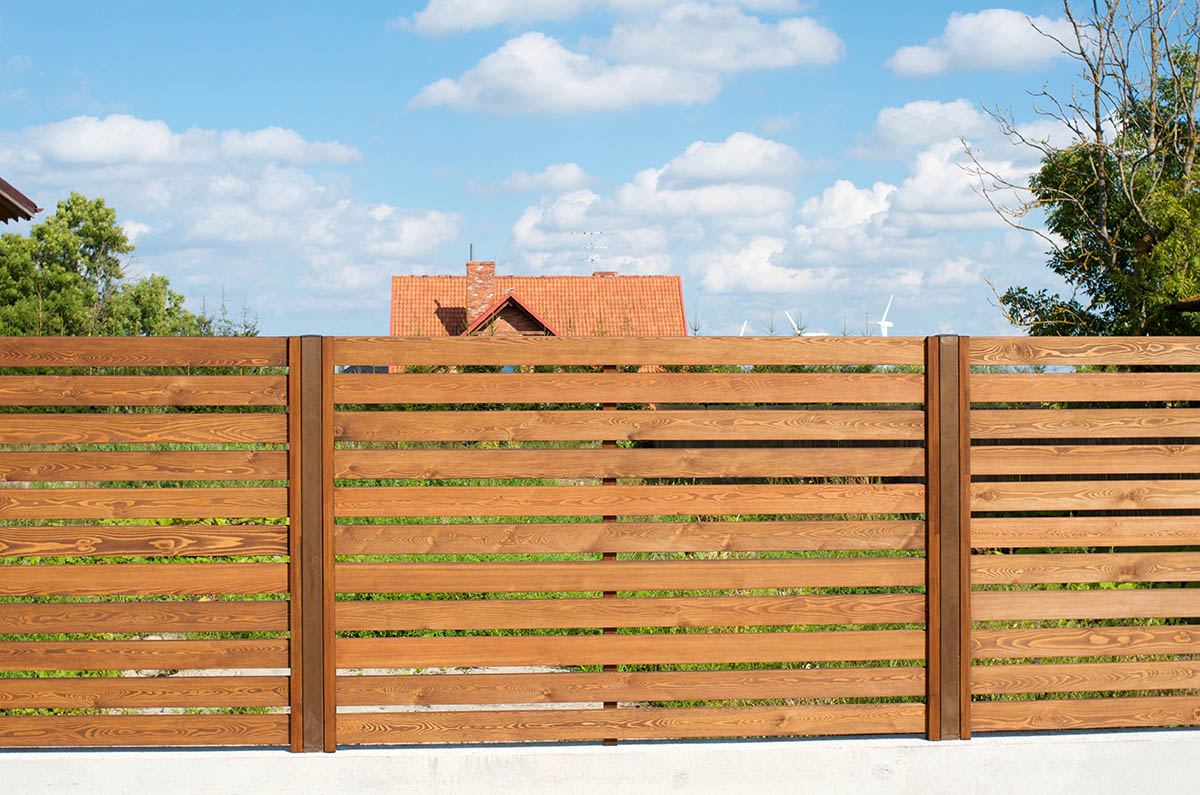 Деревянный забор на металлических столбах из обрезной доски фото